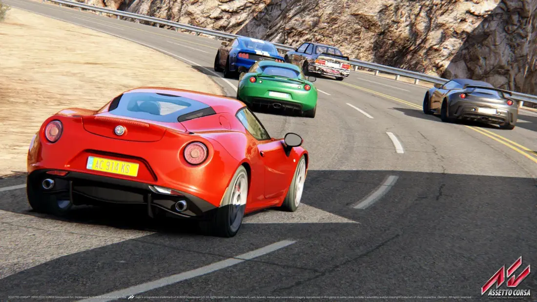 Coupé stradale rossa vista da dietro in uscita di curva su una strada di montagna, seguita da altre vetture